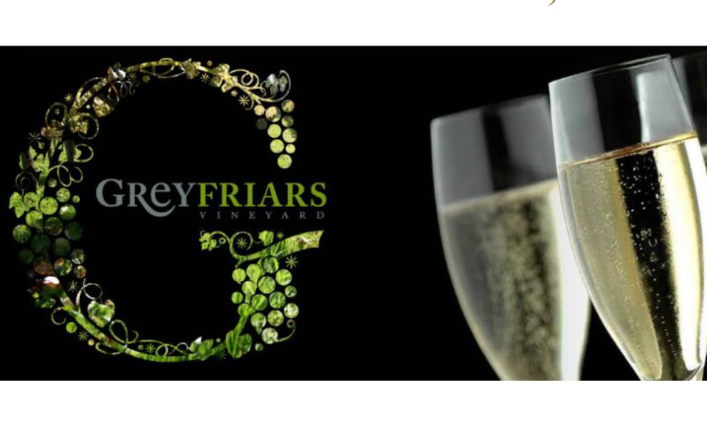 Grey friars logo, next to a champgne gladd full of bubbling champagne