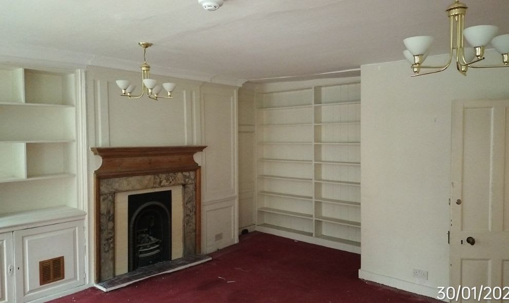 Before of a room at 17/20 Old Buildings with red carpet, shelves, and a fireplace.