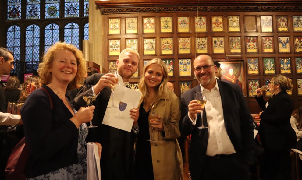 A newly Called member raising a glass of champagne with their family in the Great Hall.