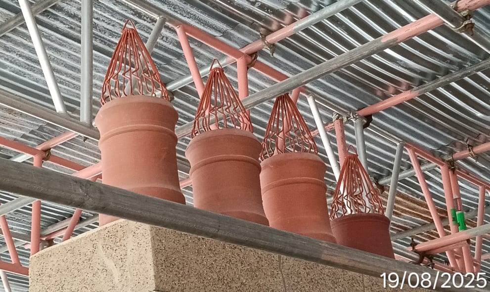 Four terracotta chimney pots with intricate pointed metal caps on a rooftop.