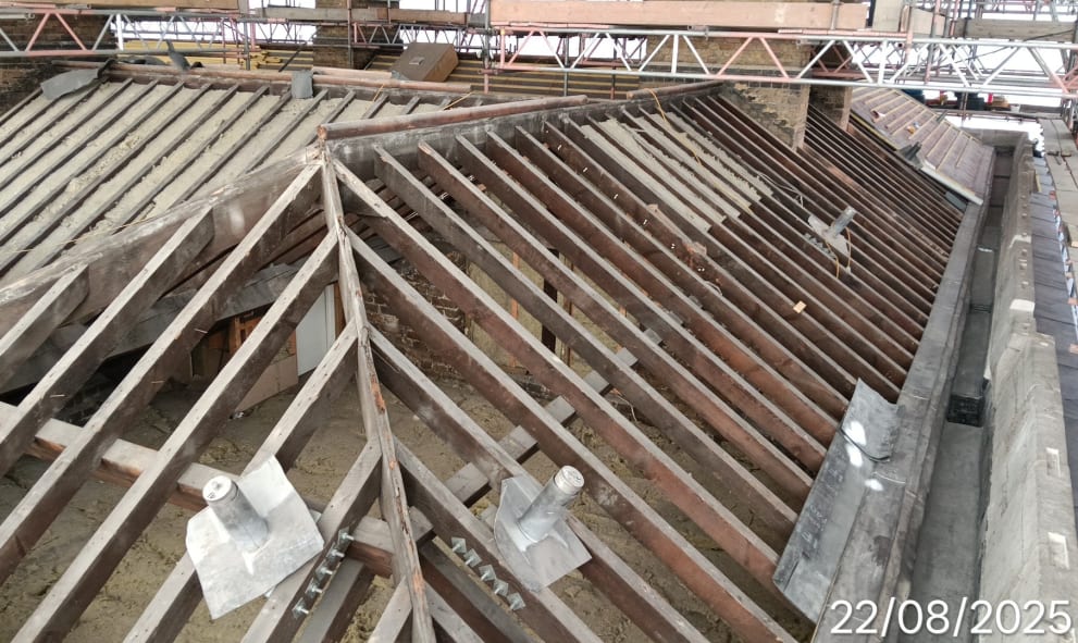 Roof under restoration with exposed wooden beams and scaffolding.