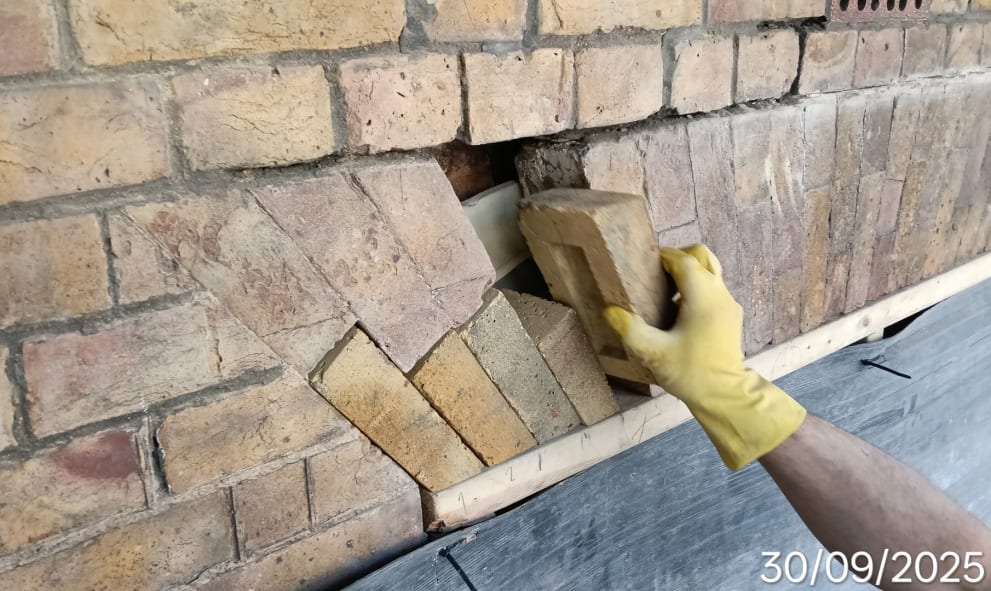 A construction worker's hand laying bricks into the walls of Stone Buildings.