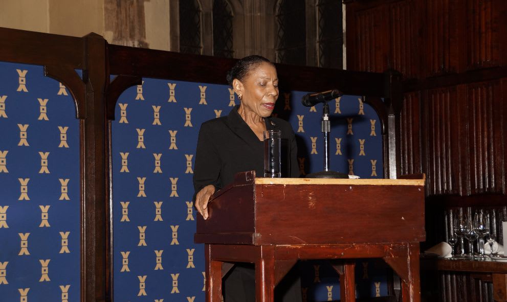 Judge Kathy Ann Brown in formal attire at a podium giving a lecture.