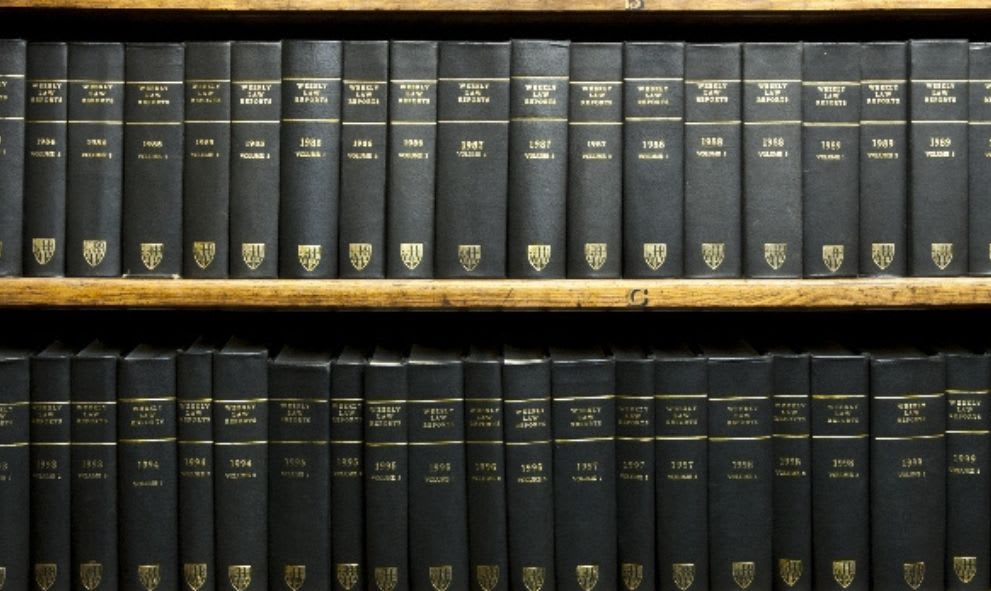Close-up of neatly arranged black-bound journals on wooden shelves, each labeled with gold text denoting years and volumes, conveying a scholarly, organized tone.