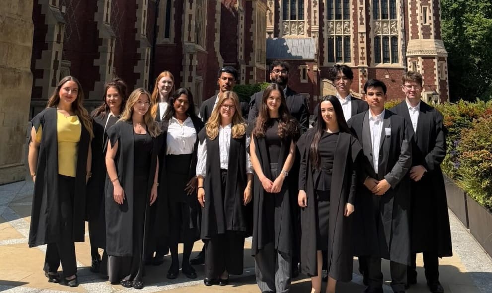 13 young men and women, Outreach prize winners 2026, pose for a group photo in black long barrister gowns on the terrace of Lincoln's Inn in the sunshine
