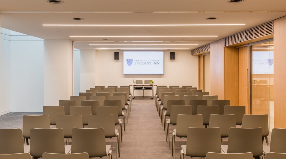 Rows of chairs set up in meeting room for seminar with display screen at front