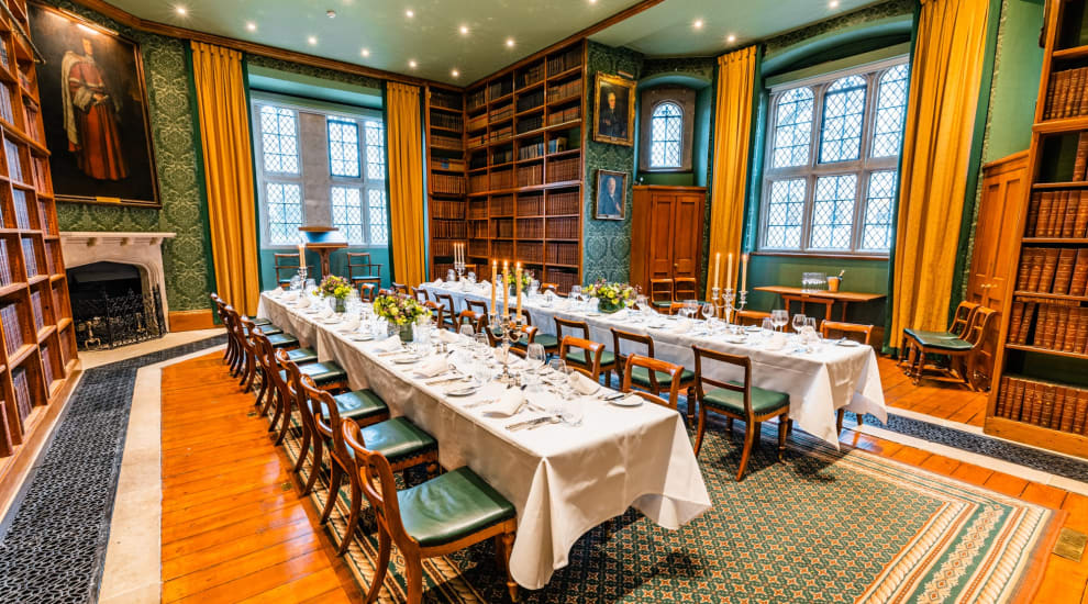 Tables decorated with candles and flowers set up for dinner in historic hall