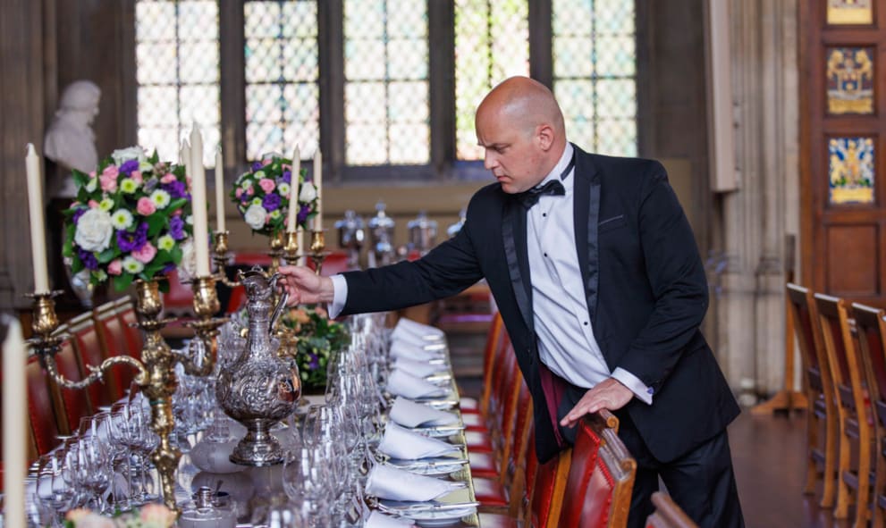 A smartly dressed man in a suit placing a candle on a well decorated table for table decor
