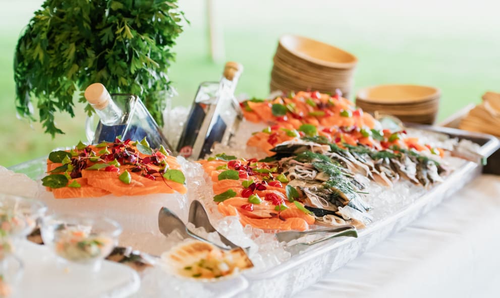 A photo of a vibrant food stall of differing types of fish. Cured salmon, scallops, and mini pots of crab