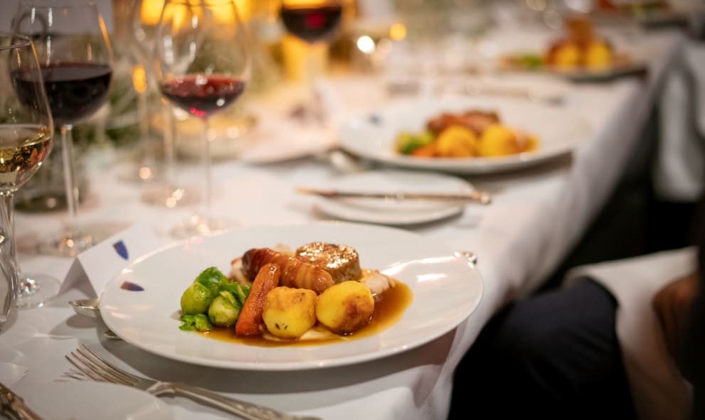 Christmas dinner on a table set for dinner with red wine and candles.