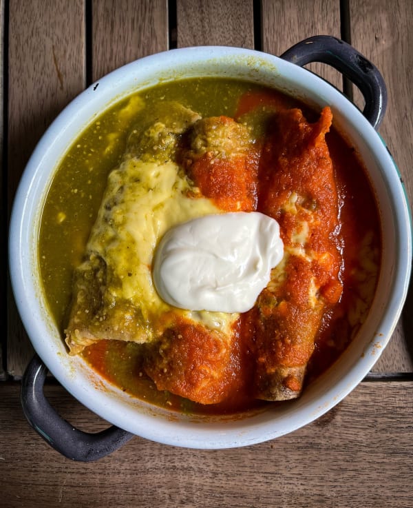 Plato de enchiladas con salsa roja y verde y crema