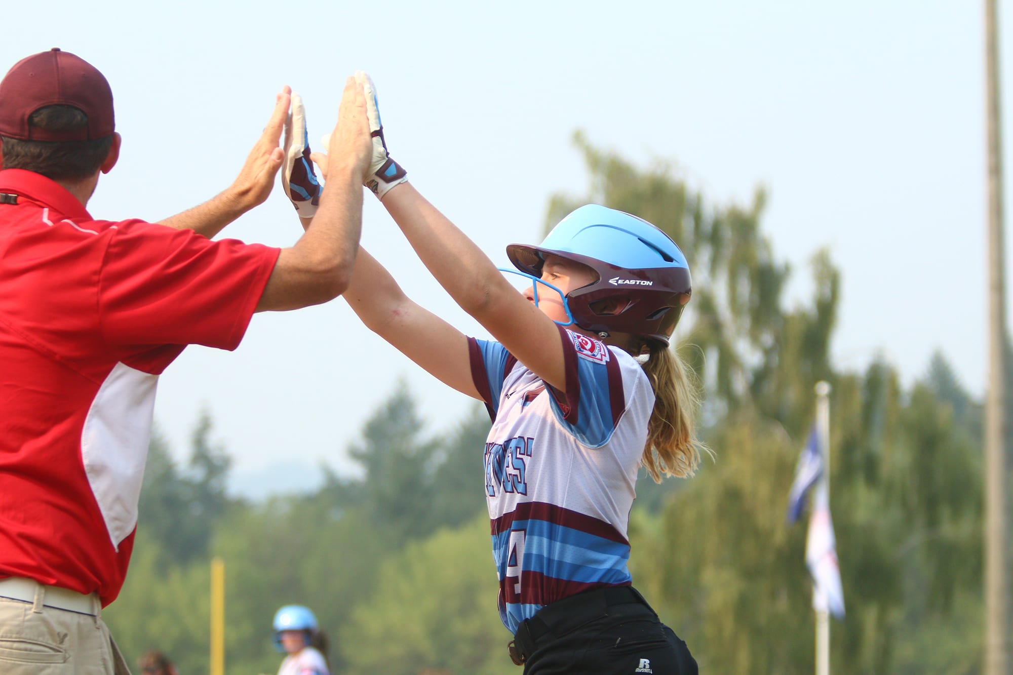 softball player high fiving coach