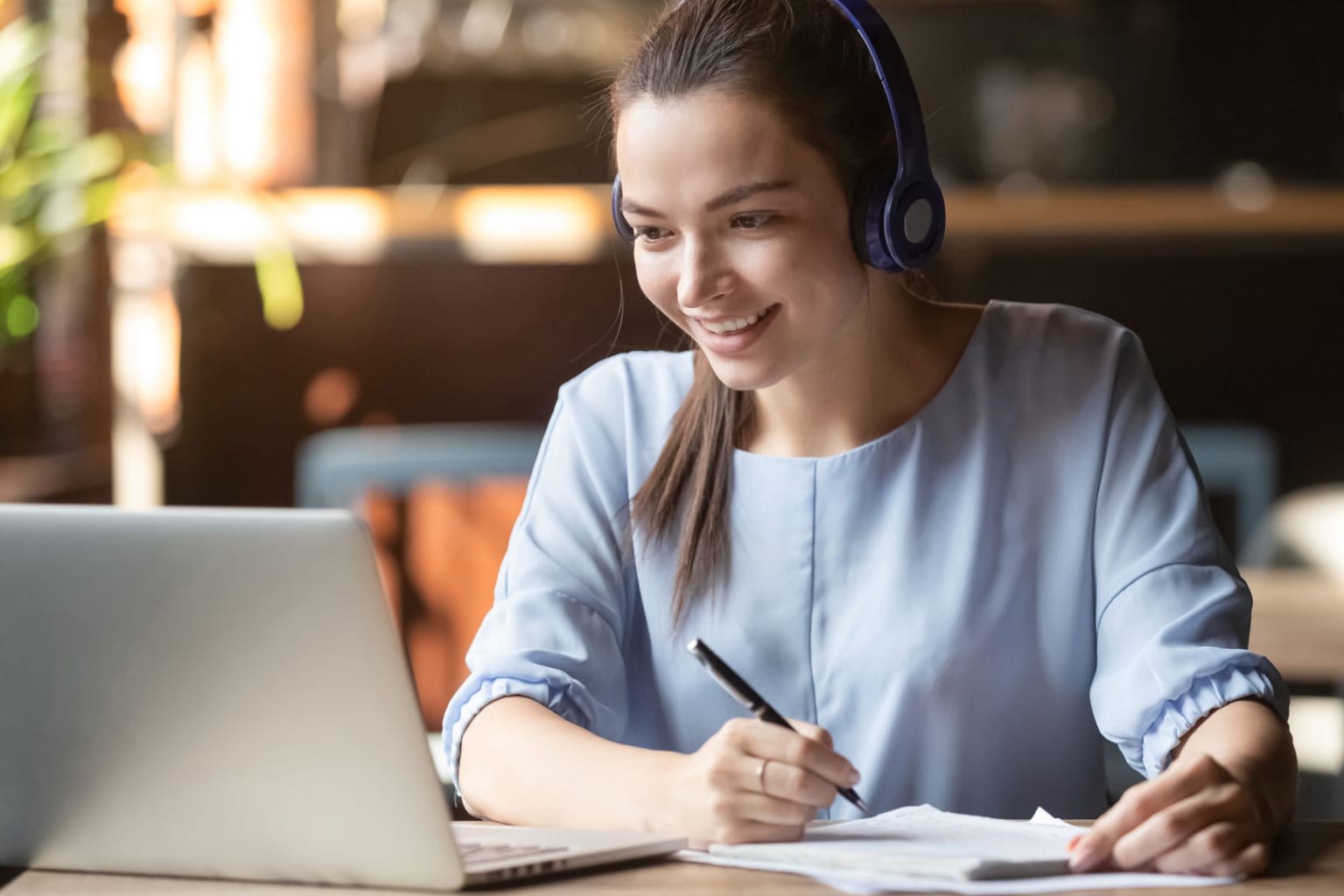 woman watching webinar taking notes