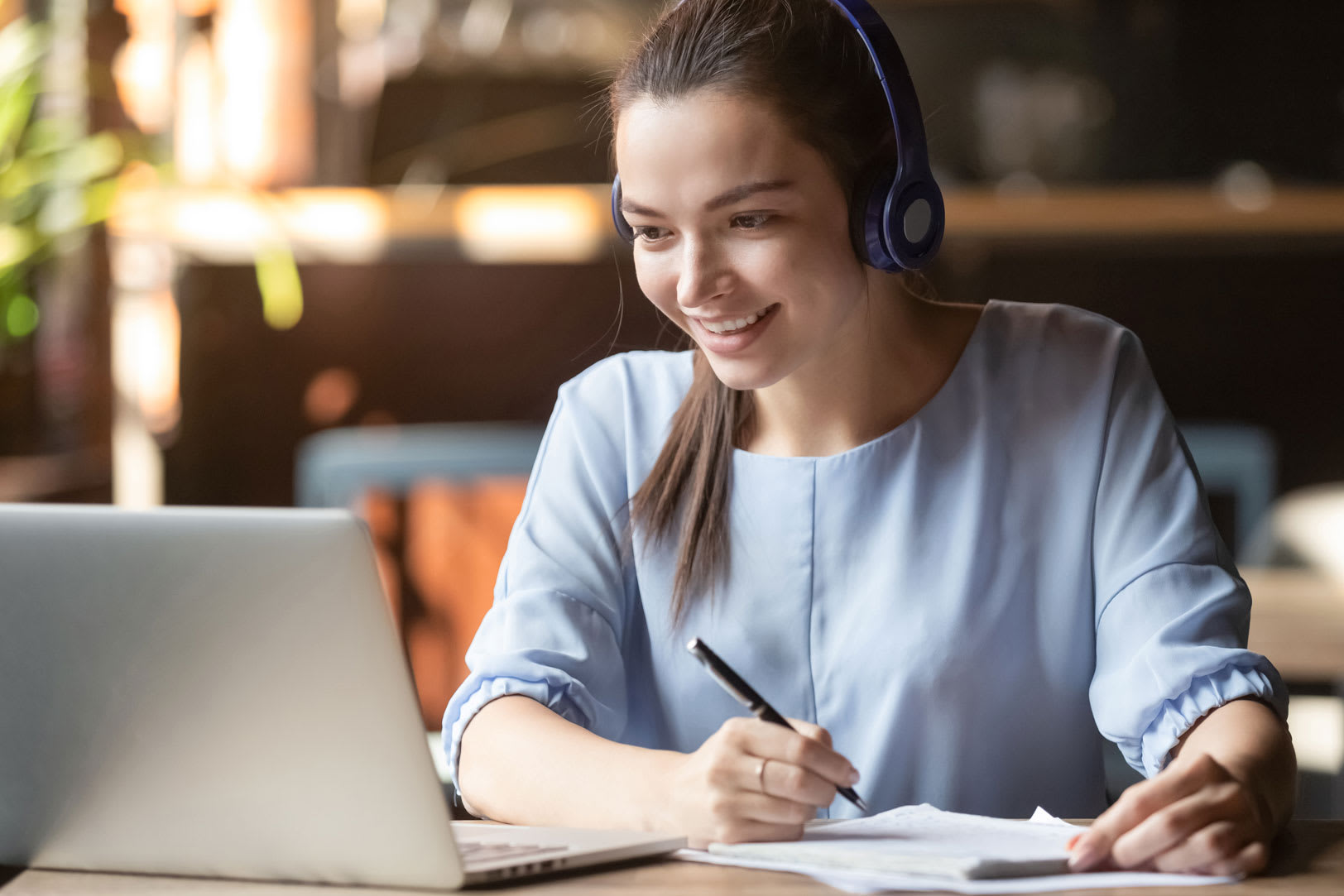 woman watching webinar taking notes