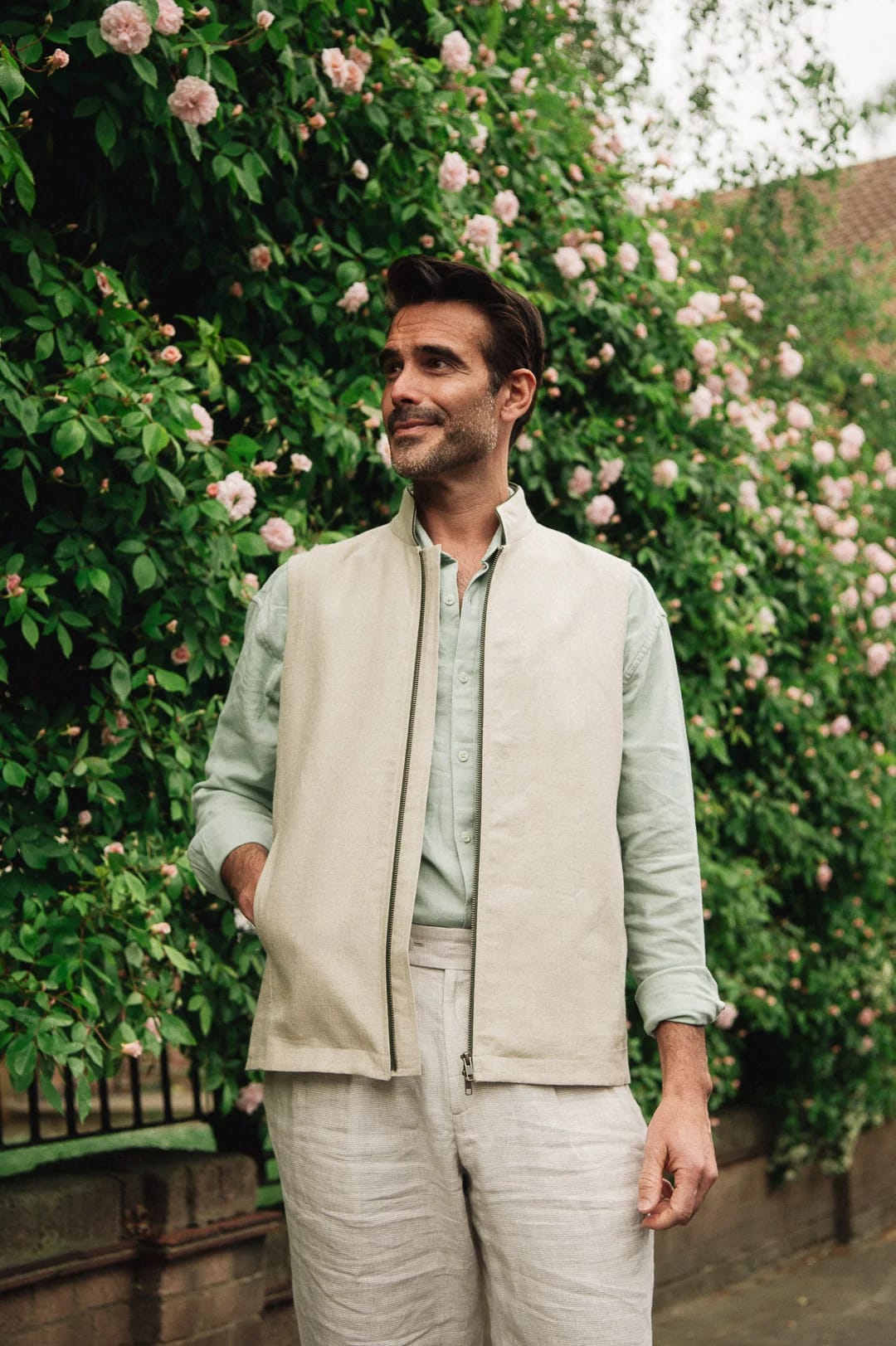 Man in a stone linen Darzi gilet in front of a climbing rose