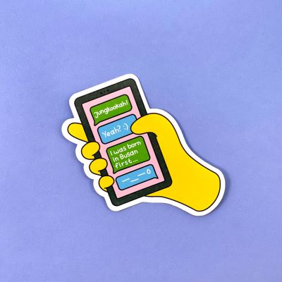 Yellow emoji hand holding black phone with text messages on the screen saying: "Jungkookah! Yeah? I was born in Busan first... –_–"