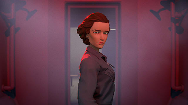 Meena, wearing a grey shirt, standing in a red room.