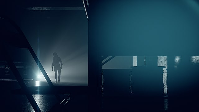The silhouette of Jess Faden walking toward a light in a dark warehouse.