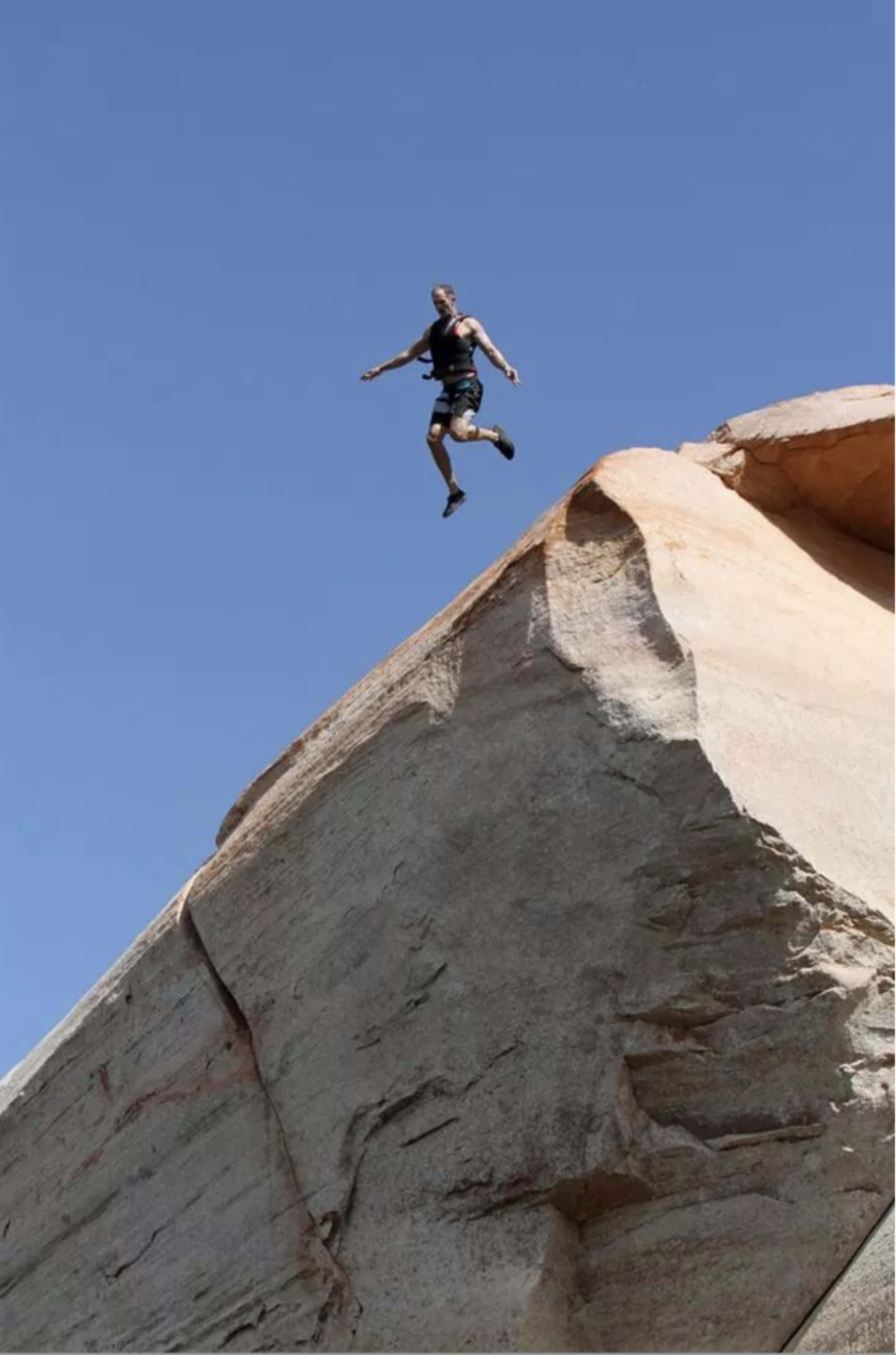 Bill leaping from a sandstone cliff into open air.