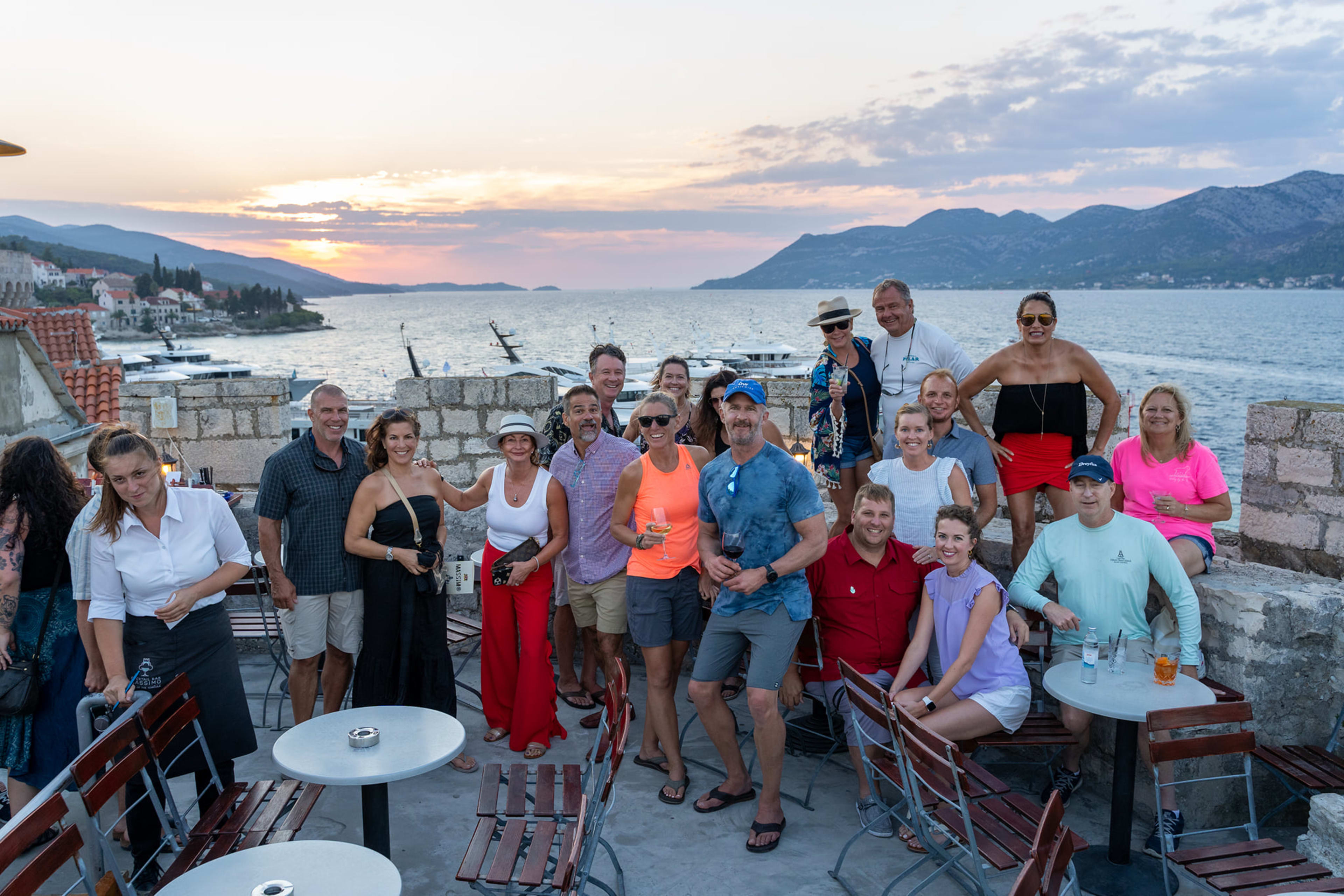 A couple of dozen friends on a Mediterranean terrace at sunset, the life the business is meant to celebrate.