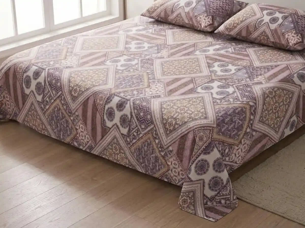 A bed dressed in a patterned quilt and matching pillowcases with a geometric patchwork design in muted purple, beige, and brown tones, shown in a bedroom setting with a window and light wood floor.
