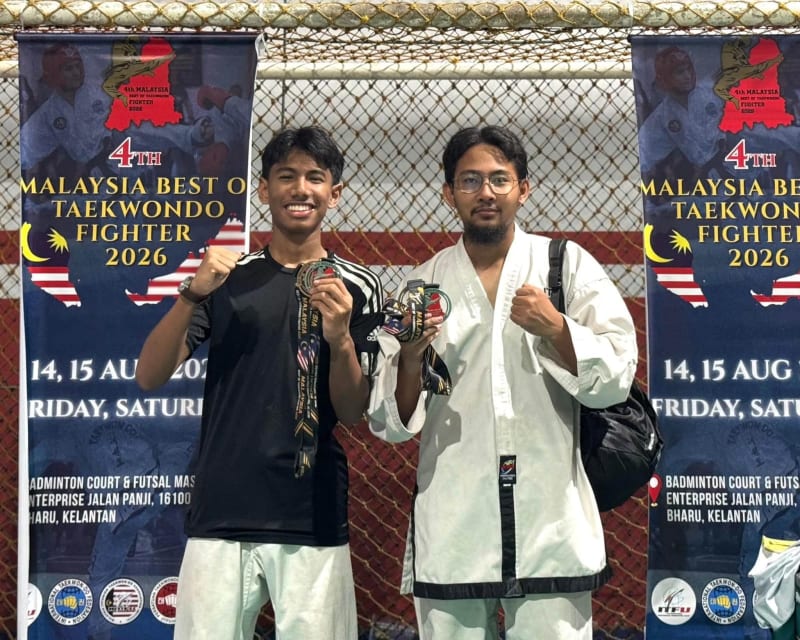 Dua pelajar MATAB menunjukkan pingat masing-masing di hadapan sepanduk 4th Malaysia Best of Taekwondo Fighter 2026