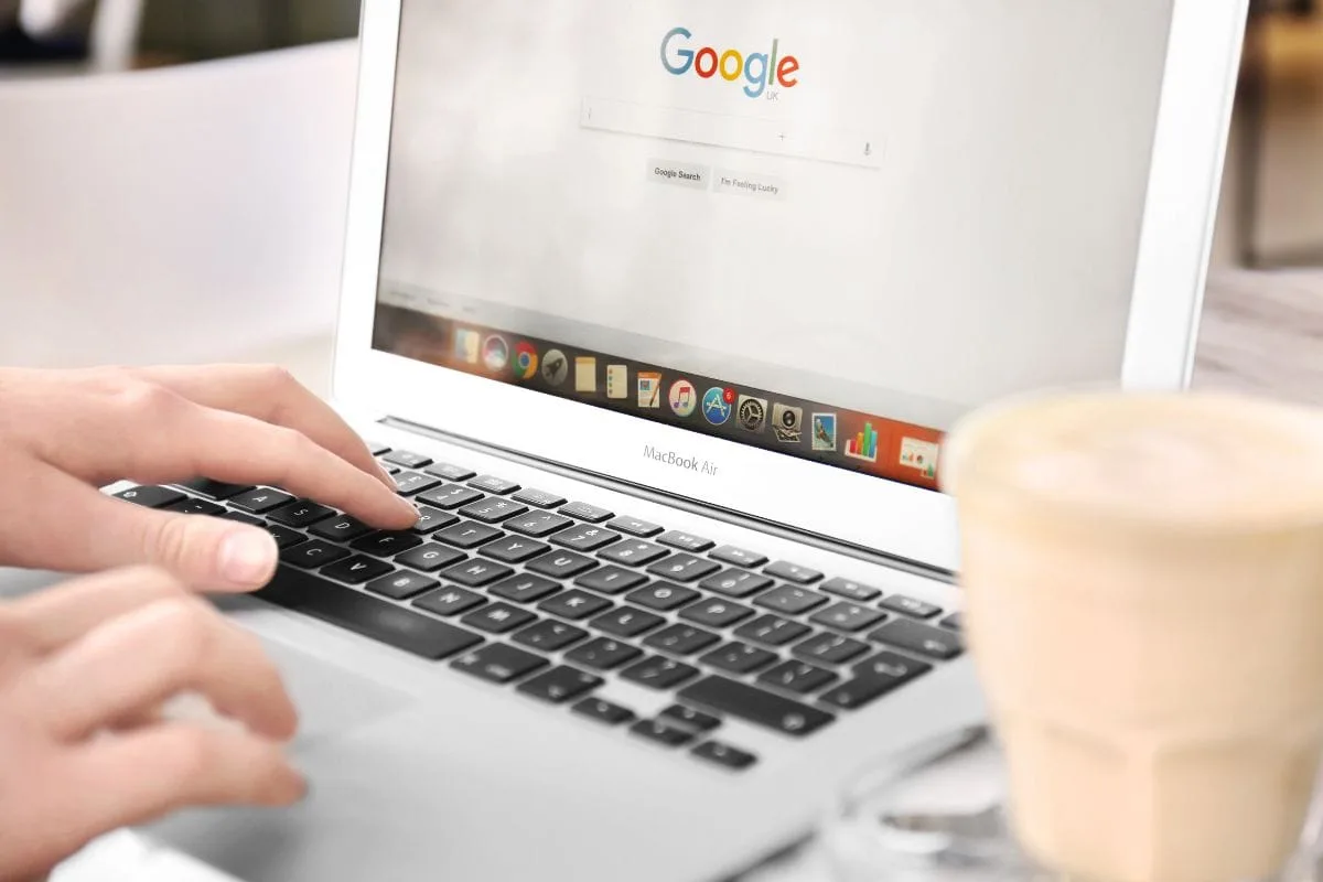 _Woman Using Laptop with Google on Screen in Cafe