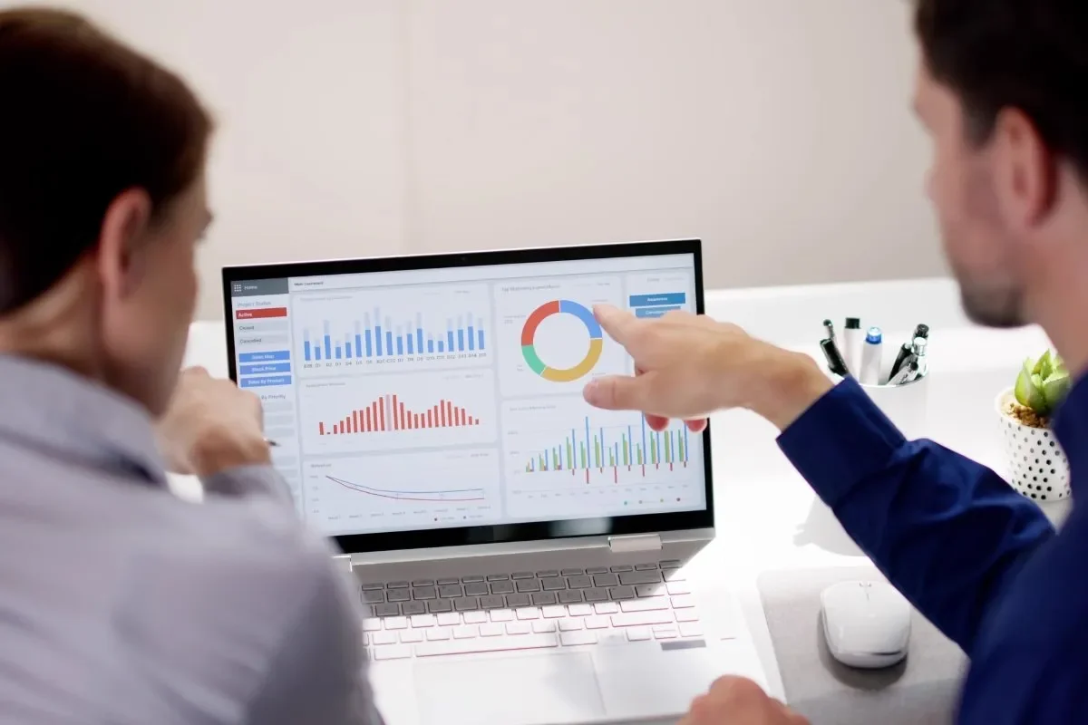 Two people analyzing lead generation metrics and KPIs on a laptop screen.
