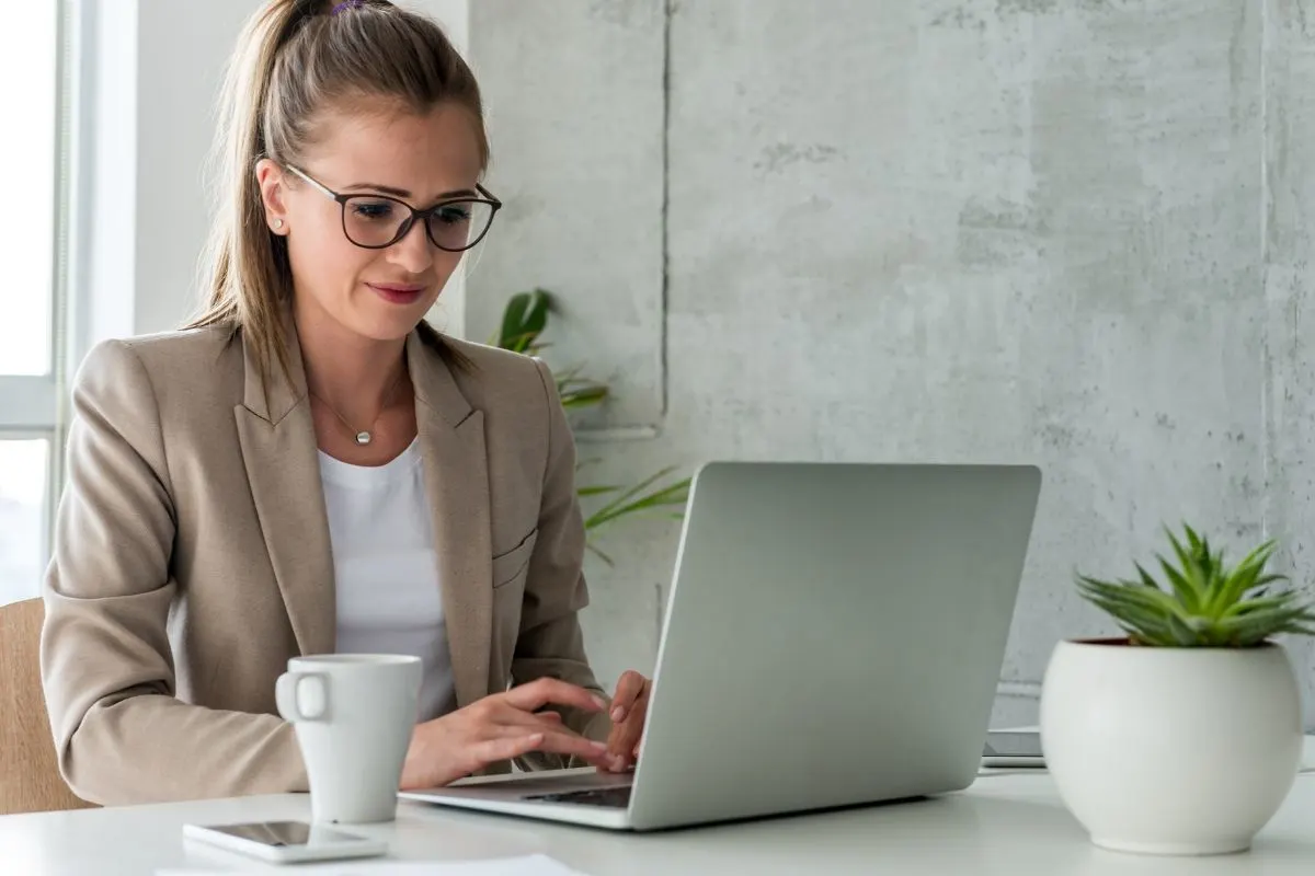 In The Office, A Business Woman Is Diligently Working On Her Laptop, Utilizing The Marketing Technology Stack To Unveil Her Power.