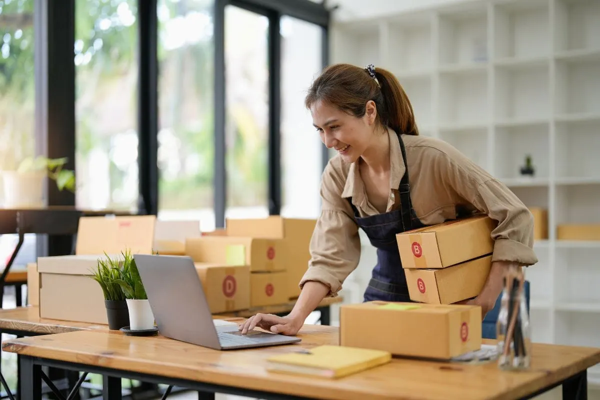 A Woman Working At A Desk, Utilizing A Laptop To Boost Business Through Local Marketing Strategies.