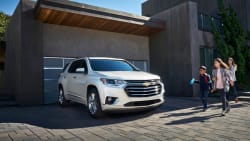 A white 2020 Chevrolet Traverse standing on a driveway with a family approaching.