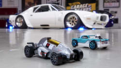 the diecast Hot Wheels models on the floor with a life-size Legends vehicle in the background.