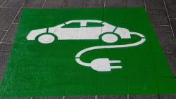 A painted green sign on the asphalt of a parking space for electric vehicle charging.
