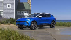 a blue Chevrolet Equinox EV on a driveway with the ocean on the background.