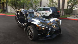 Polaris Slingshot Grand Touring beside a police car
