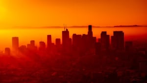 The Los Angeles skyline, with a setting sun just off to the left creating an orange glow across the city of angels