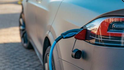 rear of a gray Tesla with a charging cable attached