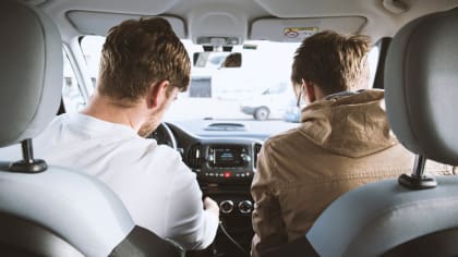 a young driver in the front seat, with their friend in the passenger seat.