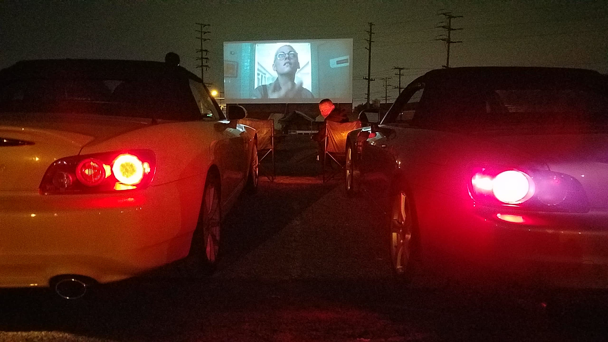 Two sports cars next to each other at a drive-in movie.