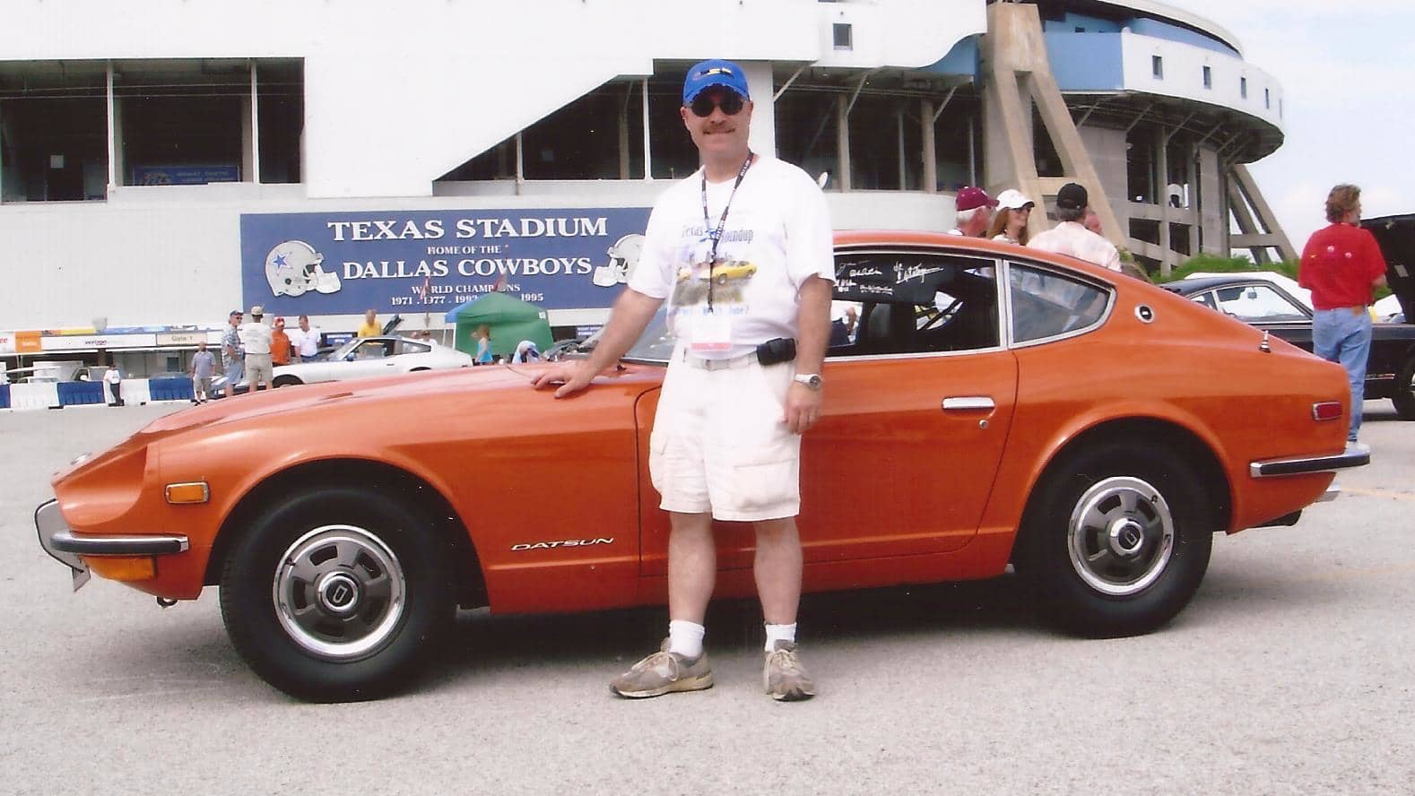 Daniel Banks in shorts in front of an orange Datsun Z.