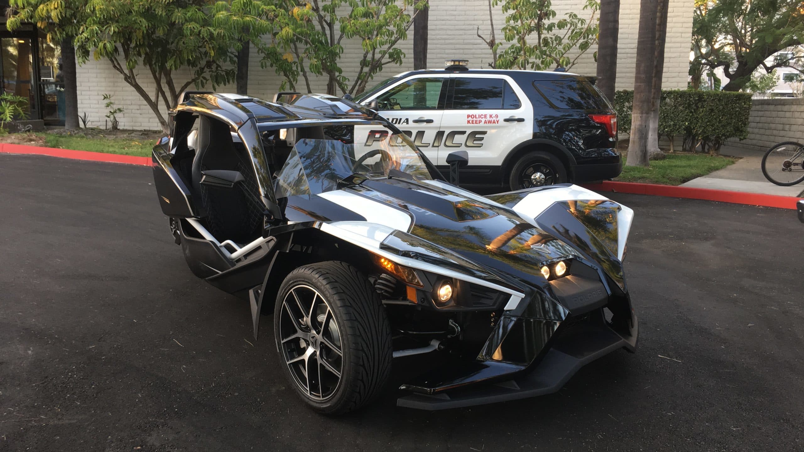 Polaris Slingshot Grand Touring beside a police car