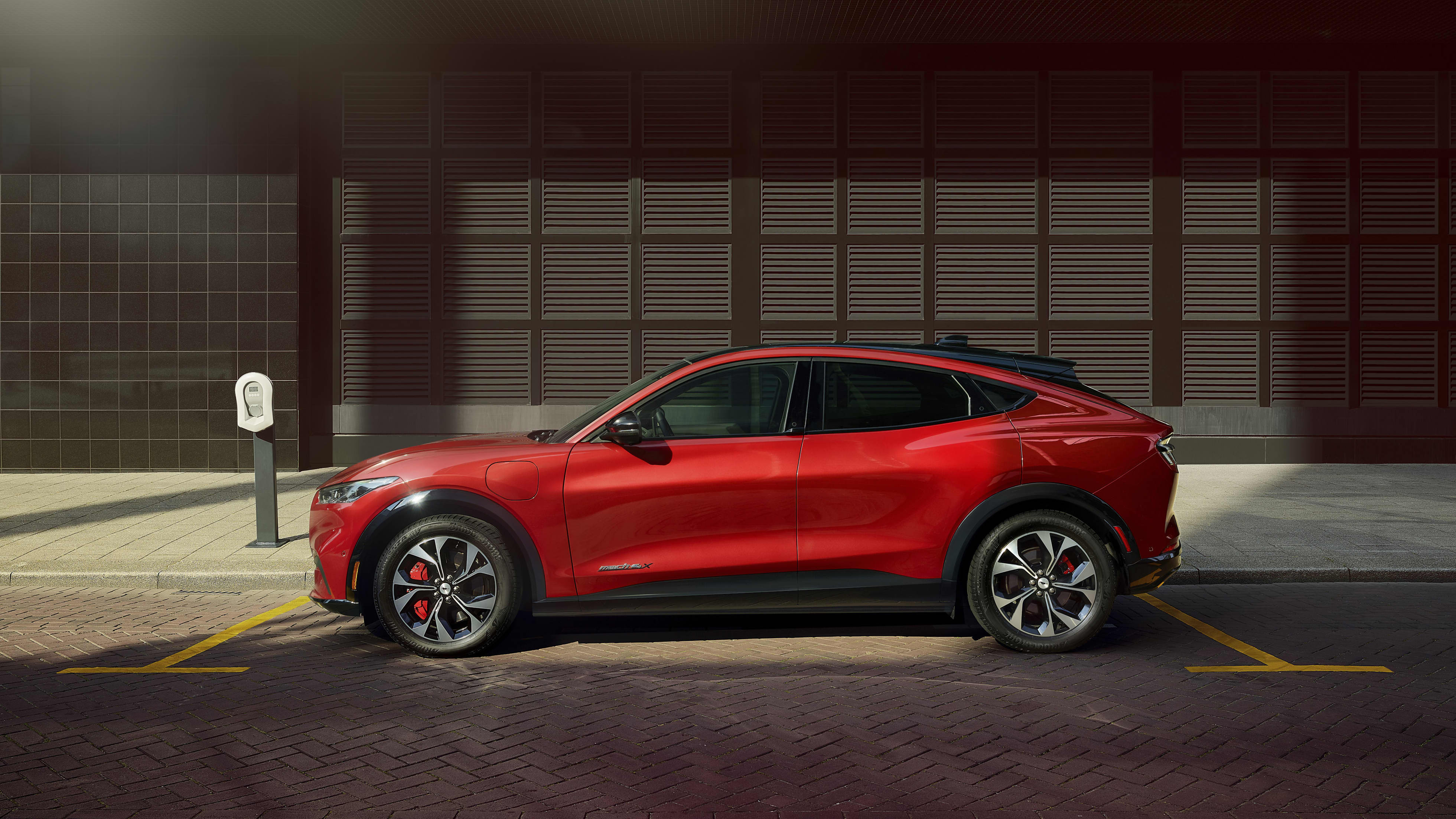 A red 2020 Ford Mach E parked in a ray of sun.