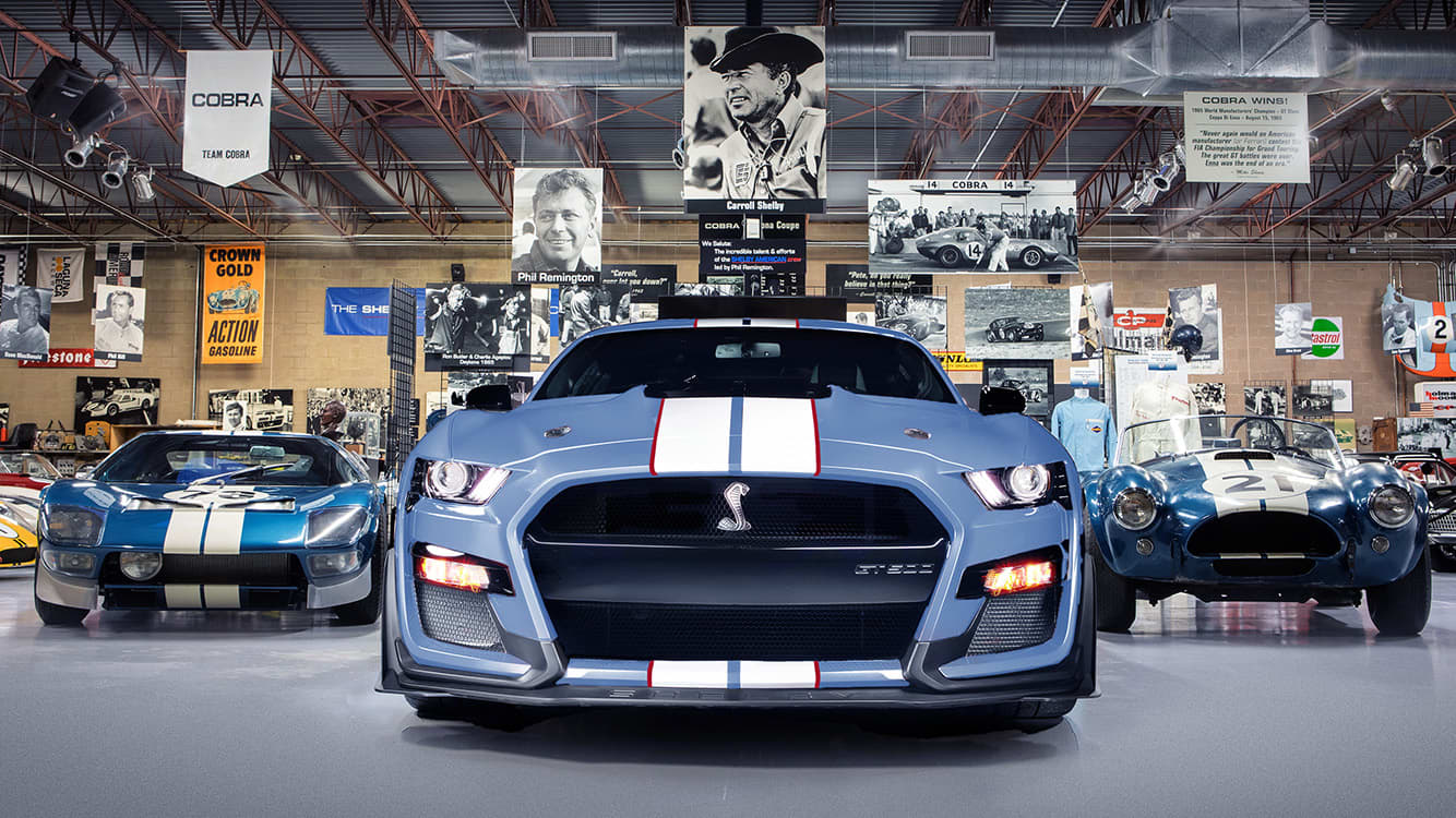 front of a blue with white stripes Ford Shelby GT500