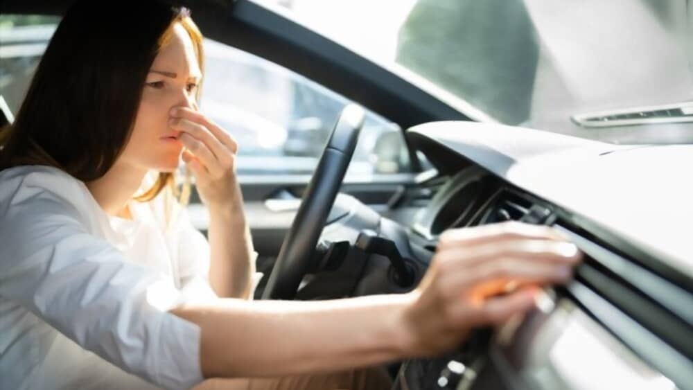 woman holding nose while sitting in car.