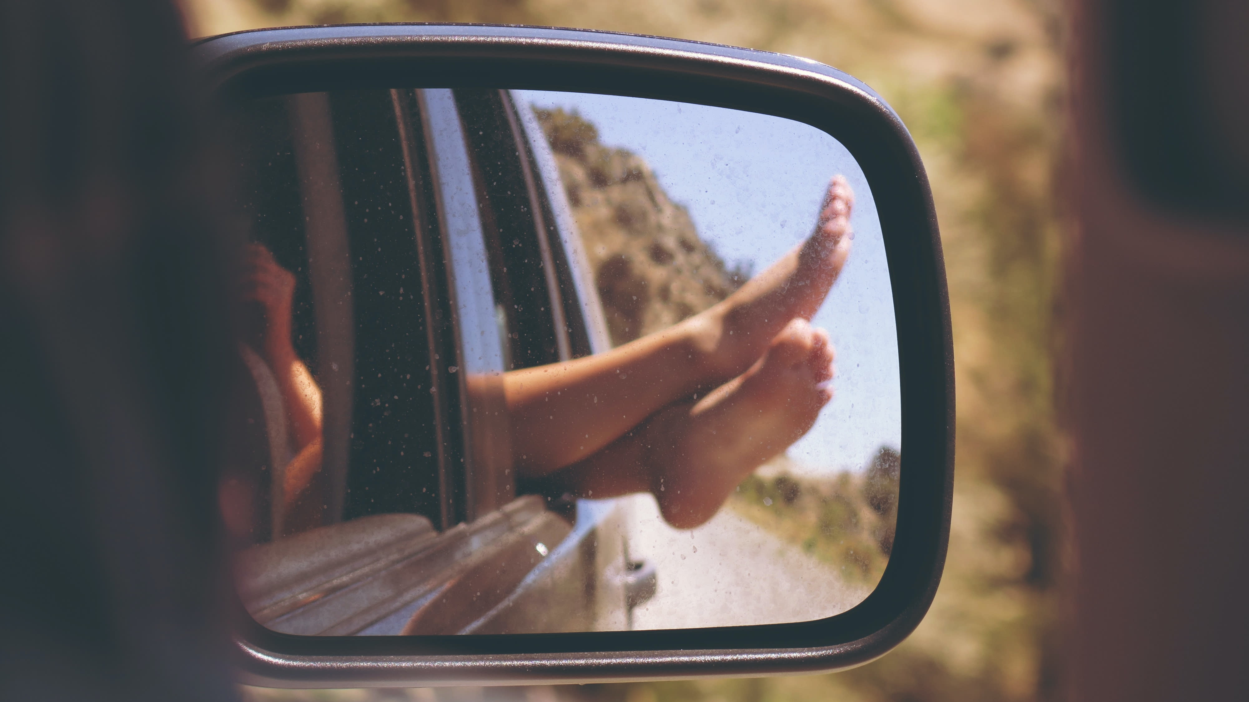 feet hanging out through the window of a family car.