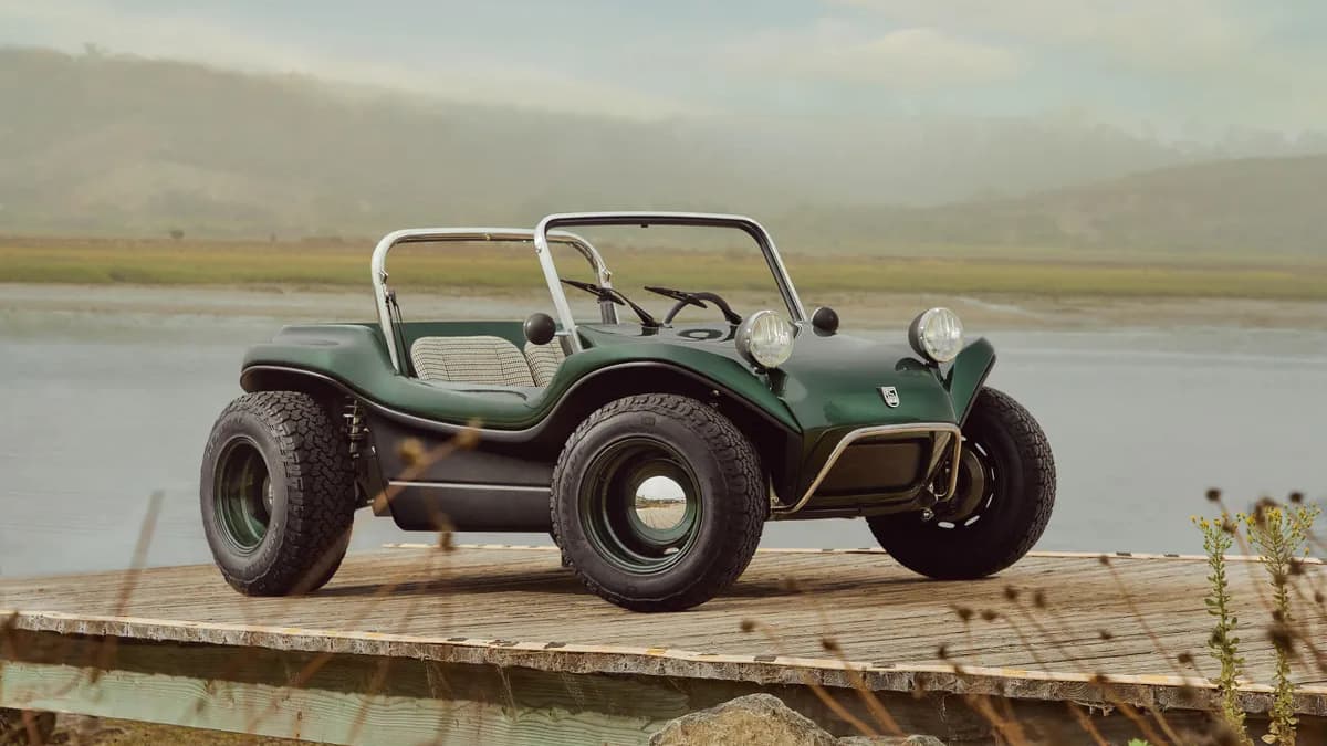A green Meyers Manx Electric Dune-buggy on a dock with a lake in the background.