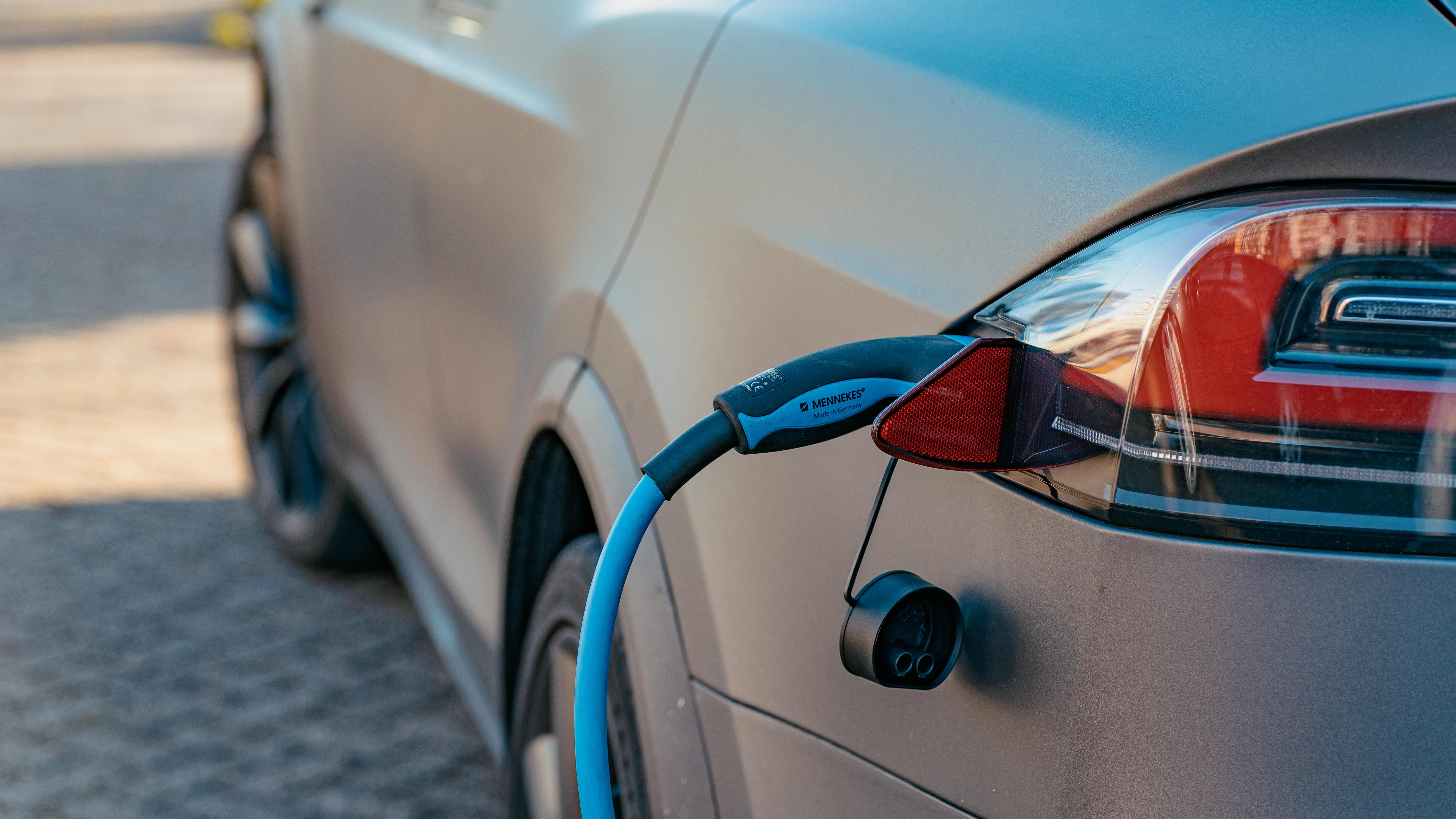 rear of a gray Tesla with a charging cable attached
