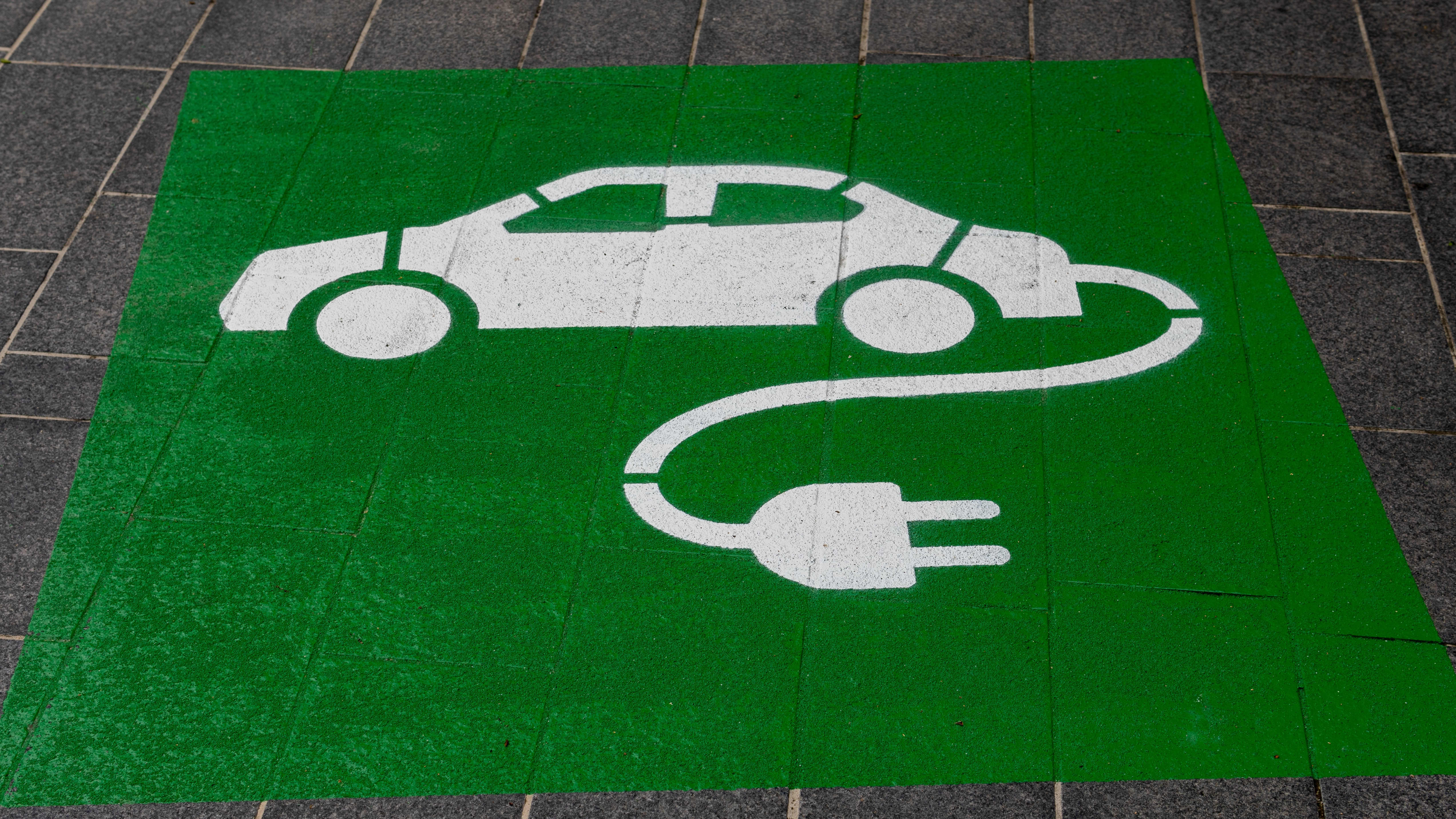 A painted green sign on the asphalt of a parking space for electric vehicle charging.