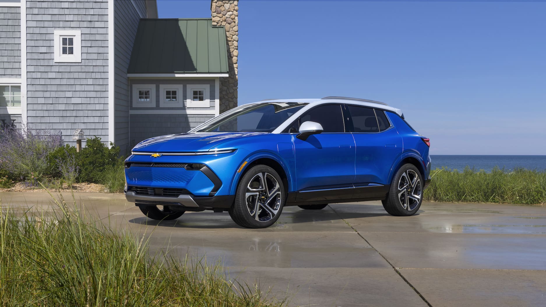 a blue Chevrolet Equinox EV on a driveway with the ocean on the background.