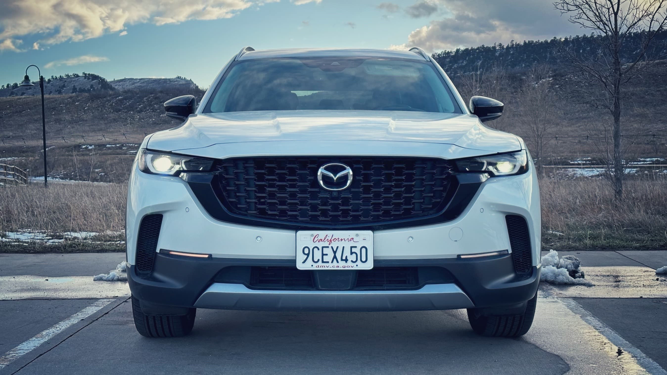 The front face of a white 2023 Mazda CX-50 in a parking lot.